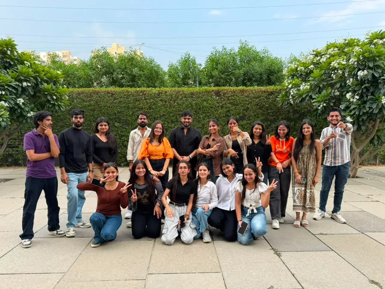The Anslation team together outdoors in front of a flowering hedge