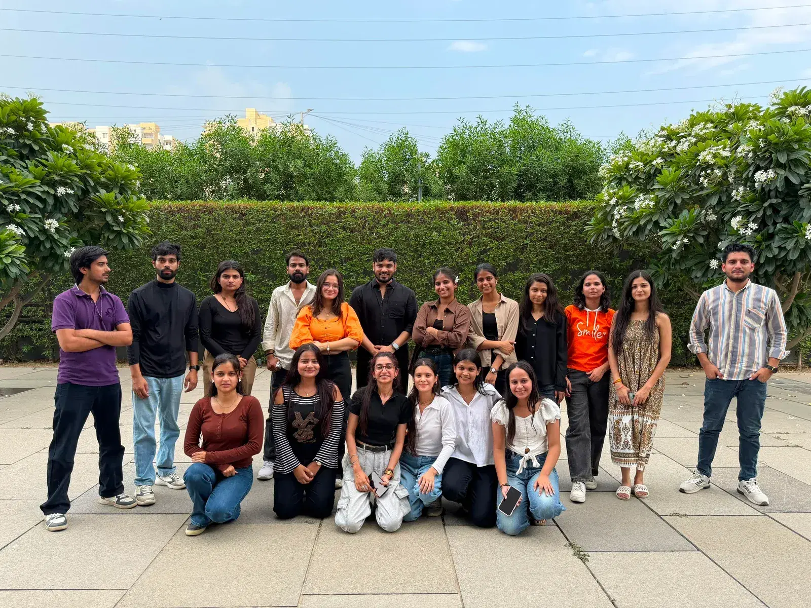 The Anslation team together outdoors in front of a flowering hedge